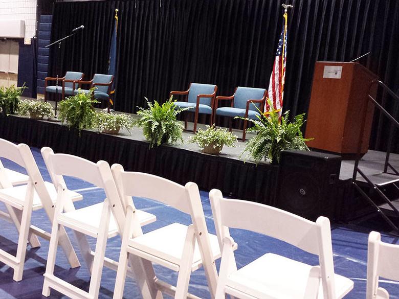 Chairs, podium, and stage set up in the gym for commencement